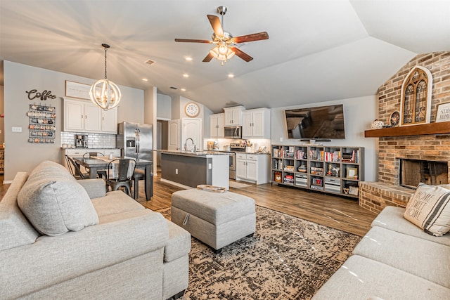 living room featuring dark hardwood / wood-style flooring, lofted ceiling, and ceiling fan with notable chandelier