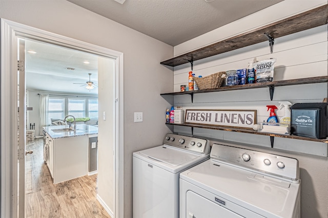 clothes washing area featuring a textured ceiling, sink, independent washer and dryer, ceiling fan, and light hardwood / wood-style flooring