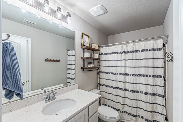 bathroom with toilet, vanity, and a textured ceiling