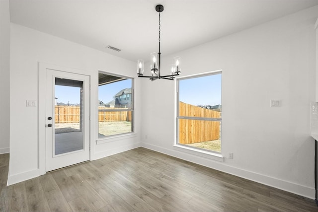 unfurnished dining area with hardwood / wood-style flooring and a chandelier