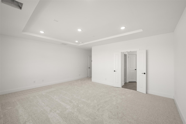 carpeted spare room featuring a raised ceiling