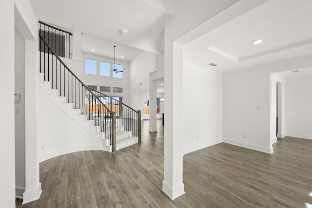 foyer with a raised ceiling, a towering ceiling, and hardwood / wood-style floors