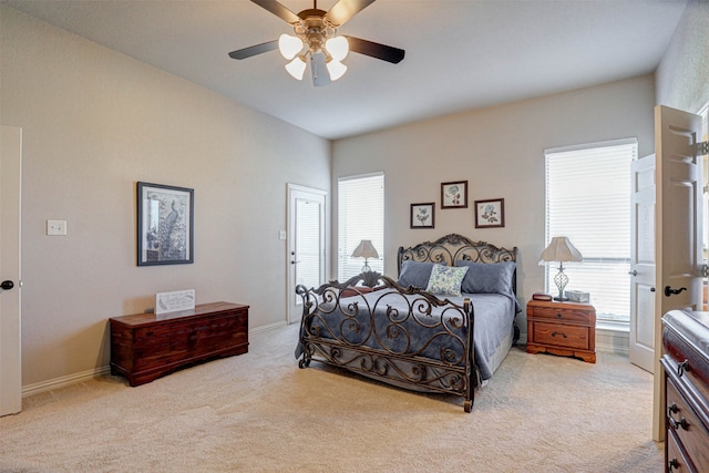 bedroom featuring ceiling fan, light colored carpet, and multiple windows