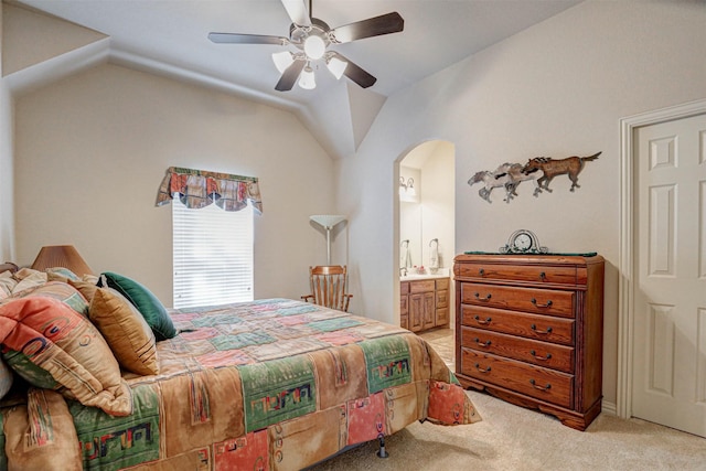 bedroom with arched walkways, lofted ceiling, light colored carpet, ensuite bathroom, and a ceiling fan