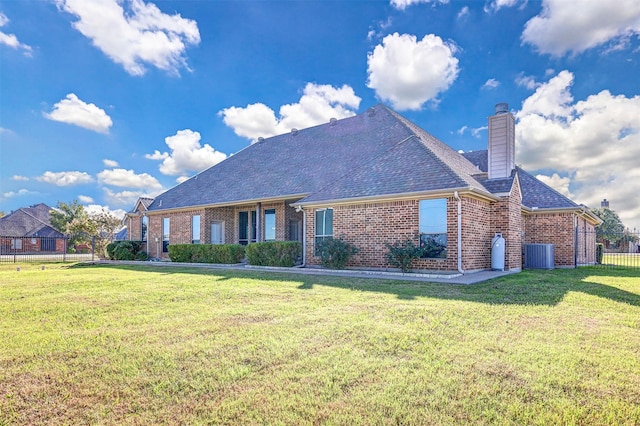 view of front of property featuring a chimney, fence, central air condition unit, a front lawn, and brick siding