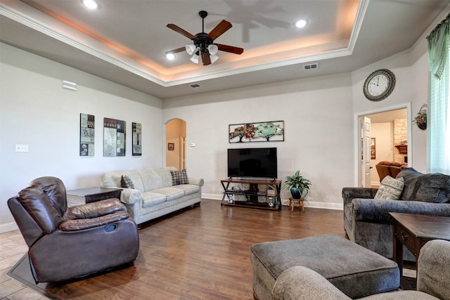 living room with a tray ceiling, ceiling fan, and hardwood / wood-style flooring