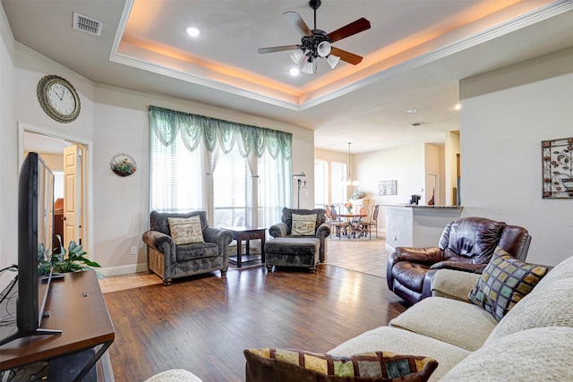 living room featuring a raised ceiling, visible vents, ceiling fan, wood finished floors, and baseboards