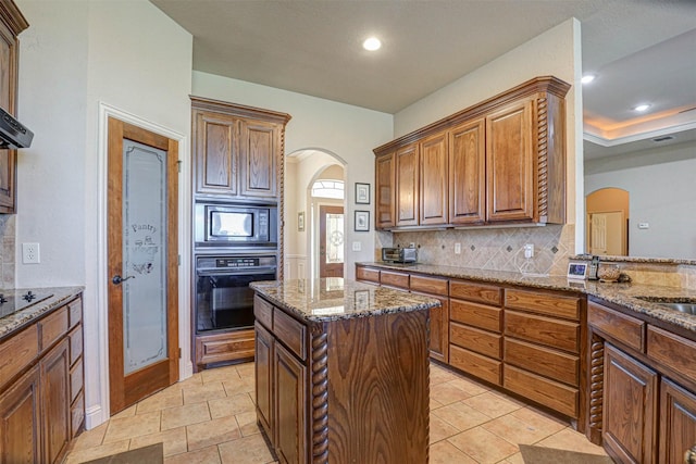 kitchen with stone counters, arched walkways, black appliances, and tasteful backsplash