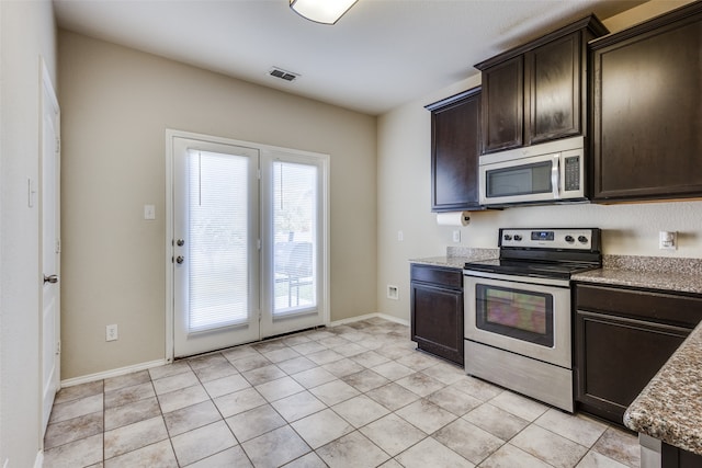 kitchen with dark brown cabinetry, light tile patterned flooring, stone counters, and appliances with stainless steel finishes