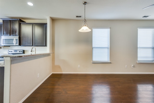 kitchen with dark brown cabinets, light stone counters, dark hardwood / wood-style floors, and plenty of natural light