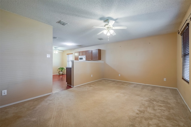 spare room with a wealth of natural light, a textured ceiling, and carpet flooring