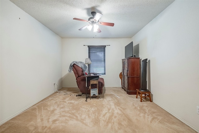 sitting room featuring ceiling fan, light colored carpet, and a textured ceiling