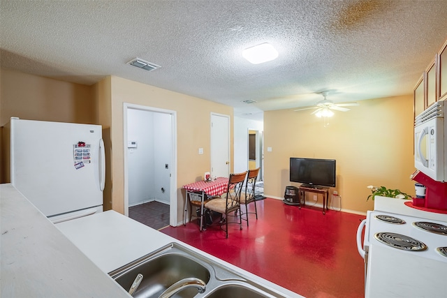 kitchen featuring white appliances, ceiling fan, and a textured ceiling