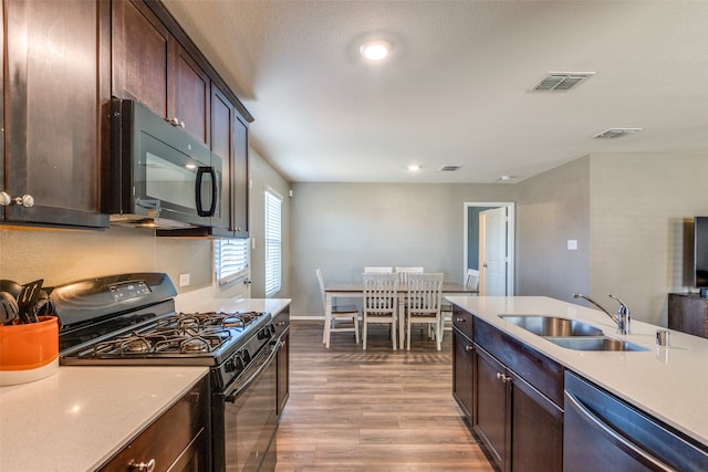 kitchen with dark brown cabinetry, dishwasher, sink, black range with gas cooktop, and light hardwood / wood-style floors