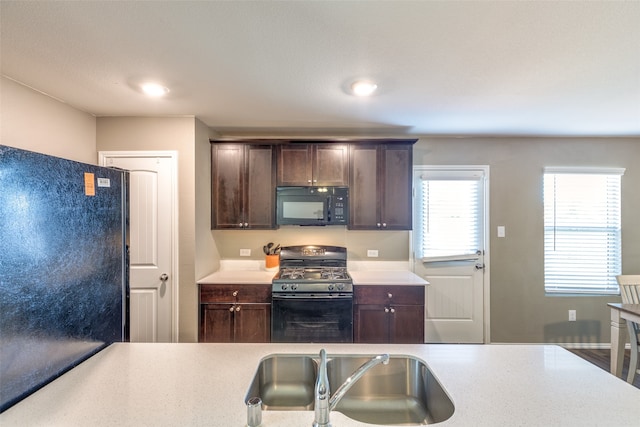 kitchen featuring dark brown cabinets, sink, hardwood / wood-style flooring, and black appliances