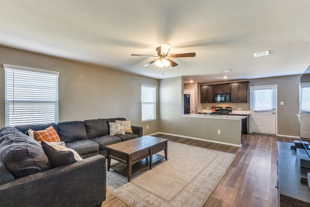 living room featuring dark hardwood / wood-style flooring, ceiling fan, plenty of natural light, and a textured ceiling