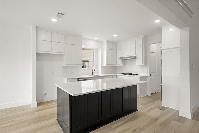 kitchen with white cabinets, a center island, light hardwood / wood-style floors, and sink