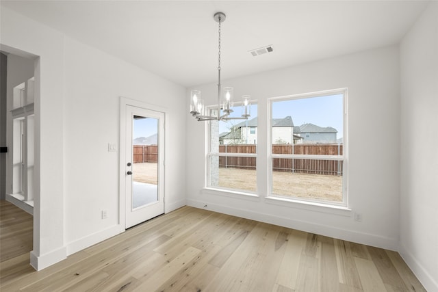 unfurnished dining area with light wood-type flooring and a notable chandelier