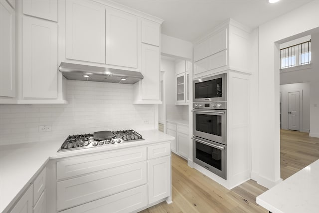 kitchen featuring light hardwood / wood-style floors, backsplash, white cabinetry, and stainless steel appliances