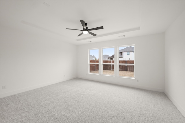 carpeted spare room featuring ceiling fan and a tray ceiling