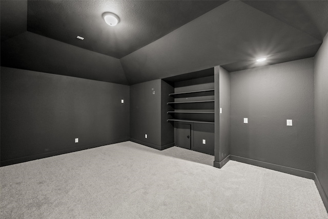 additional living space with a textured ceiling, lofted ceiling, built in features, and light carpet