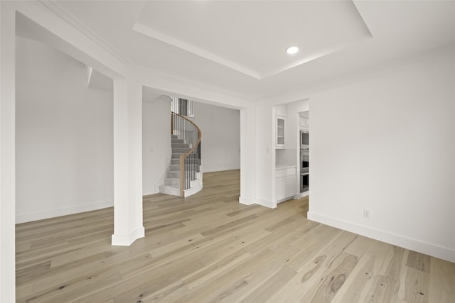 interior space with crown molding, light hardwood / wood-style flooring, and a raised ceiling