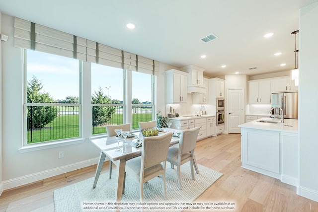 dining area with plenty of natural light, sink, and light hardwood / wood-style flooring