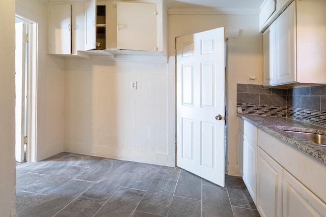 kitchen featuring sink, crown molding, white cabinetry, and backsplash