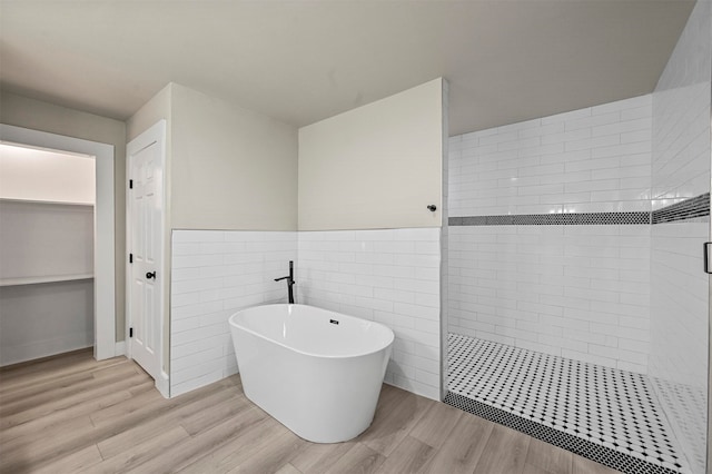 bathroom with wood-type flooring, tile walls, and independent shower and bath