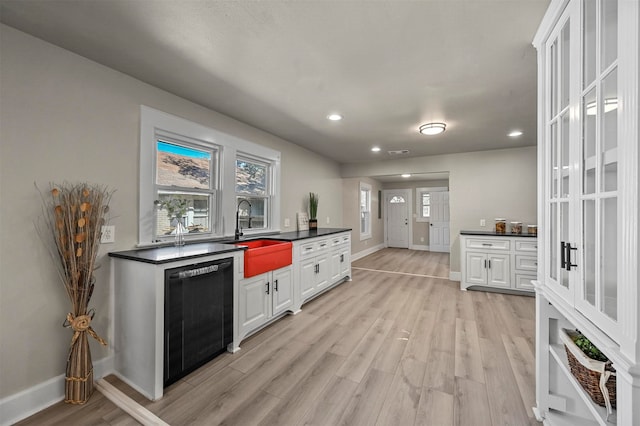 kitchen featuring white cabinets, black dishwasher, light hardwood / wood-style flooring, and sink