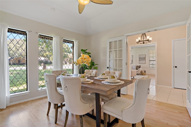 dining space with ceiling fan with notable chandelier and light hardwood / wood-style floors