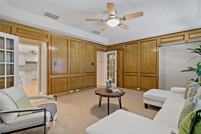 carpeted living room featuring ceiling fan and a textured ceiling