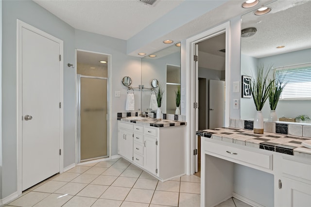 bathroom with vanity, walk in shower, tile patterned floors, and a textured ceiling