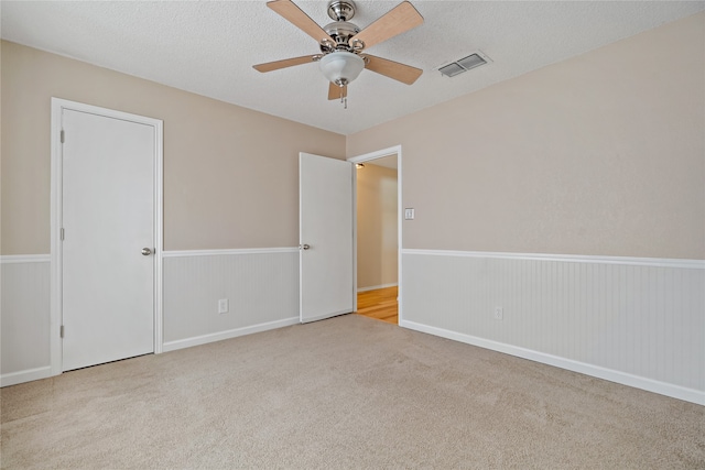 carpeted empty room featuring ceiling fan and a textured ceiling