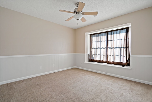 carpeted empty room with ceiling fan and a textured ceiling