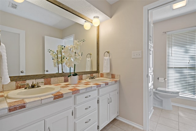 bathroom with vanity, toilet, tile patterned floors, and a textured ceiling