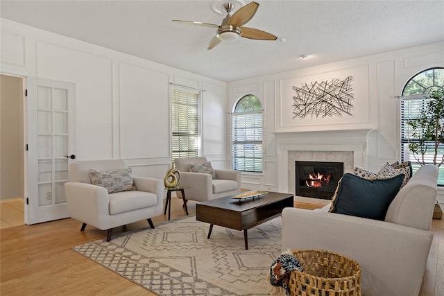 living room with ceiling fan, light hardwood / wood-style floors, and a textured ceiling