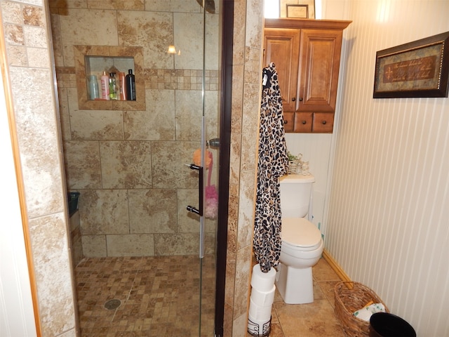 bathroom featuring toilet, tile patterned floors, and a tile shower