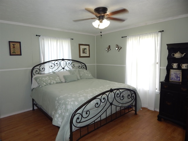 bedroom featuring hardwood / wood-style flooring, ceiling fan, multiple windows, and crown molding