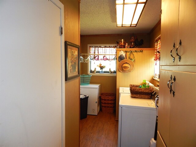 laundry room with wood walls, washing machine and dryer, a textured ceiling, and light hardwood / wood-style floors