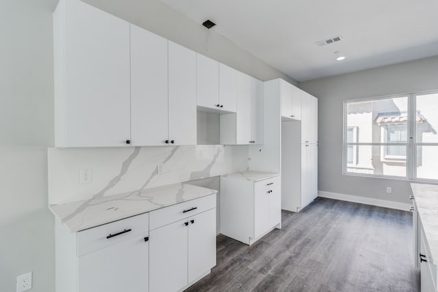 kitchen with dark wood-type flooring, white cabinetry, decorative backsplash, and light stone counters