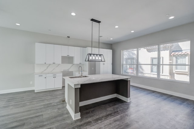 kitchen with dark hardwood / wood-style flooring, hanging light fixtures, sink, white cabinets, and a kitchen island with sink