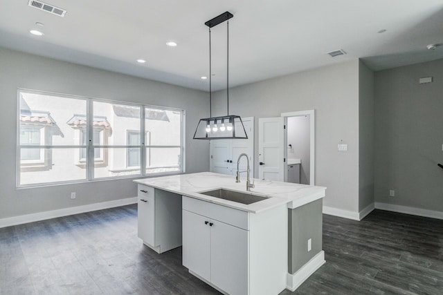 kitchen featuring dark wood-type flooring, white cabinets, sink, an island with sink, and decorative light fixtures