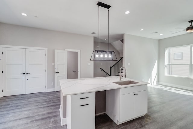 kitchen featuring sink, white cabinetry, decorative light fixtures, and a kitchen island with sink