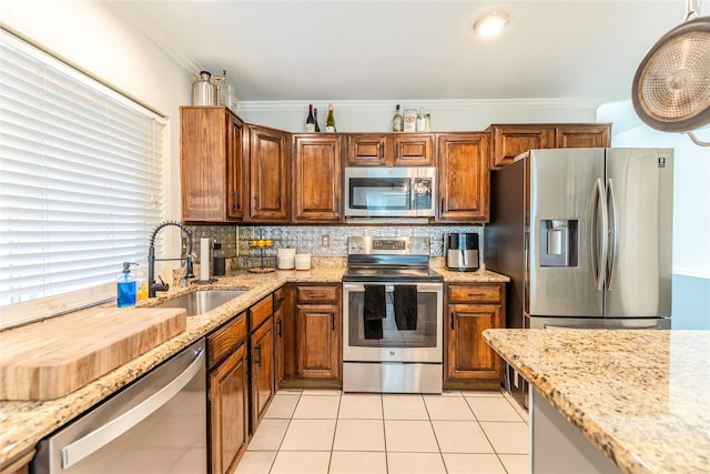 kitchen featuring light tile patterned flooring, stainless steel appliances, ornamental molding, and sink