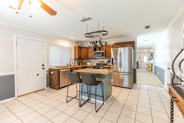 kitchen featuring a kitchen island, stainless steel appliances, and ornamental molding