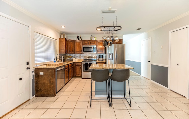 kitchen featuring a center island, light stone counters, crown molding, and appliances with stainless steel finishes