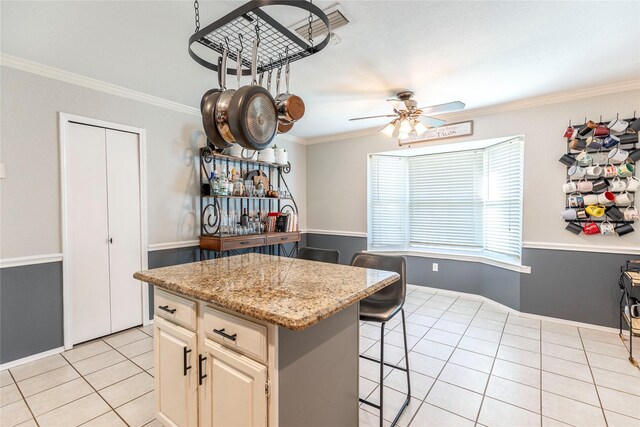 kitchen featuring light stone countertops, a kitchen breakfast bar, crown molding, light tile patterned floors, and a center island