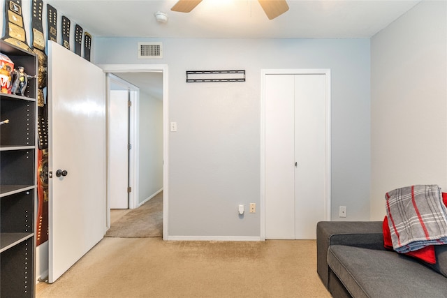 living area featuring light carpet and ceiling fan