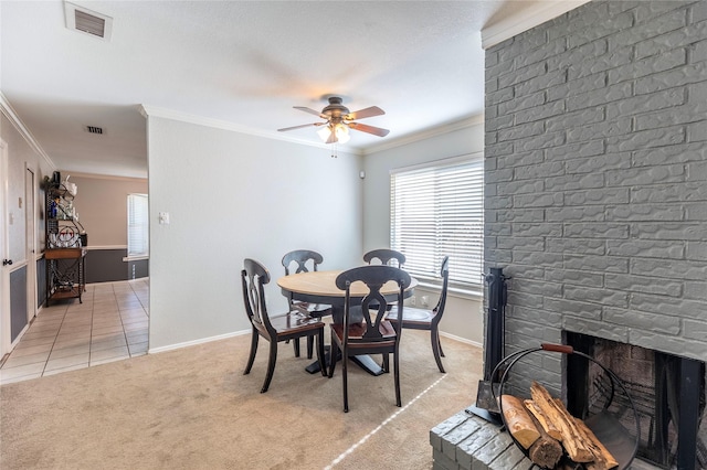 dining room featuring ceiling fan, light colored carpet, a fireplace, and crown molding